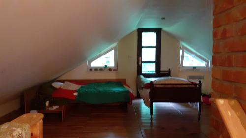 a attic room with a bed and two windows at Dom wśród drzew i pól. in Handzlówka