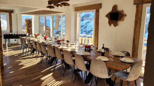 une longue salle à manger avec une longue table et des chaises dans l'établissement Chalet le Chantelevent for 24 Guests - Slope Views, Pool & Jacuzzi, à Vars