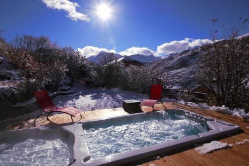 a jacuzzi tub with two chairs in the snow at Chalet le Chantelevent for 24 Guests - Slope Views, Pool & Jacuzzi in Vars