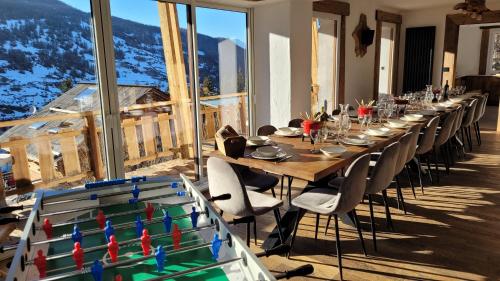 une grande table en bois avec des chaises et une grande fenêtre dans l'établissement Chalet le Chantelevent for 24 Guests - Slope Views, Pool & Jacuzzi, à Vars