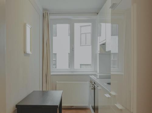 een witte keuken met een tafel en een raam bij HeyMi Apartments Schwedenplatz in Wenen