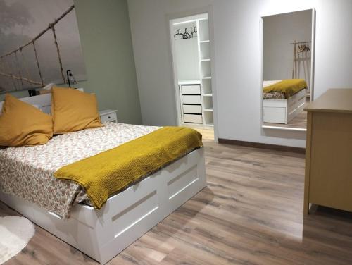 1 dormitorio con cama con almohadas amarillas y espejo en Tuty, en Málaga