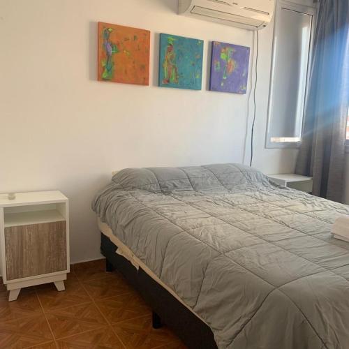 1 dormitorio con 1 cama y pinturas en la pared en Poeta Lugones 38 en Córdoba