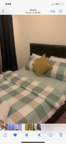 1 cama con sábanas blancas y verdes a cuadros en City Views Apartment en Bawaleshi