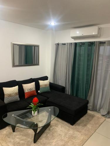 sala de estar con sofá negro y mesa de cristal en City Views Apartment en Bawaleshi