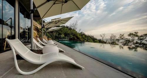 a group of chairs and an umbrella next to a pool at Wenzhou Ban Hotel in Banping