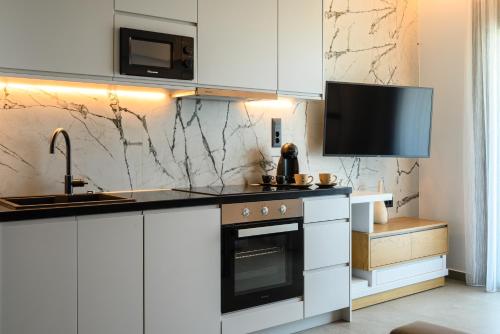 a kitchen with white cabinets and a sink and a stove at Amare Studios in Agios Nikolaos