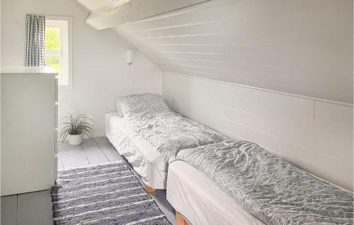 two beds in a room with white walls at Beautiful Home In Sjernary With House Sea View in Nedstrand