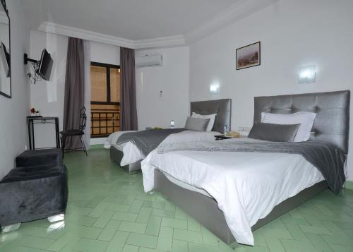 Habitación de hotel con 2 camas y TV en Hotel Nouzha en Fez