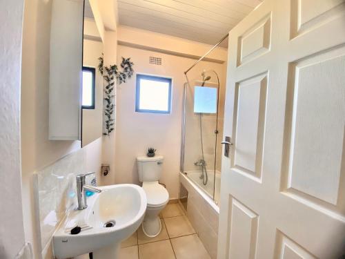a bathroom with a sink and a toilet and a door at The Ultimate Escape - Backup Electricity in Gaborone