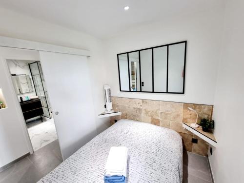 une chambre avec un lit et un miroir au mur dans l'établissement Appartement moderne et confort, à Palavas-les-Flots