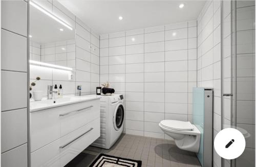 a white bathroom with a washing machine in it at Private room in sharded apartment at Løren in Oslo