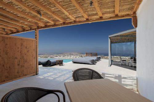 a patio with tables and chairs and a view of the ocean at Sunset Hill Suites in Mýkonos City