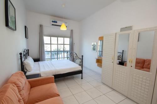 a bedroom with a bed and a couch and a window at Relaxing Private Rooms in Compound Housing near Burj Alarab Villa 124 in Dubai