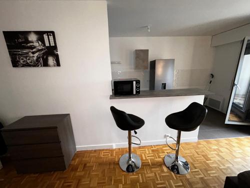 - deux tabourets dans une pièce avec un comptoir et une cuisine dans l'établissement Bel appart de 45m2 à courbevoie, à Courbevoie