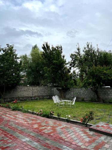 two white chairs sitting in the grass in a yard at Paradiso Lodge Skardu in Skardu