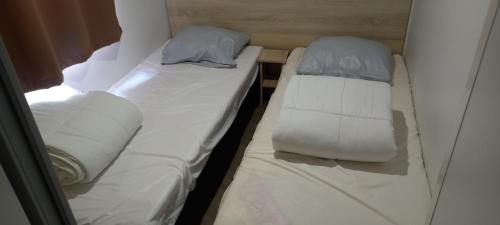 Cette petite chambre comprend 2 lits avec des draps et des oreillers blancs. dans l'établissement MH 502 Bois Dormant annexe, à Saint-Jean-de-Monts