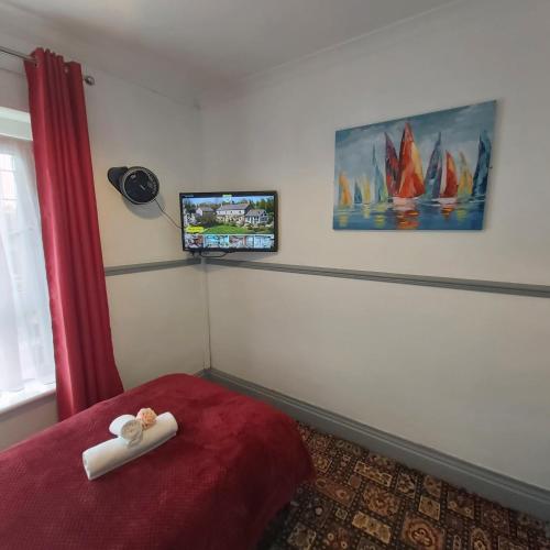 a bedroom with a bed with a tv on the wall at St Albans Guest House, Dover in Dover