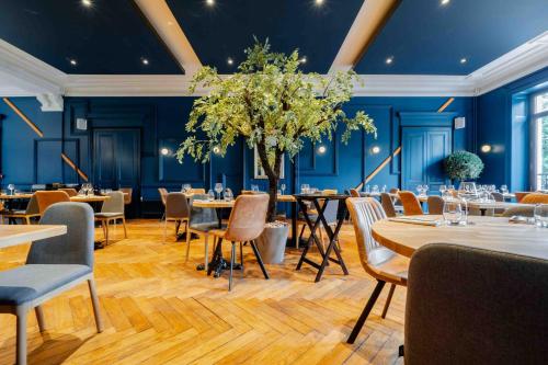 a dining room with tables and chairs and a tree at Hôtel Gallia in Aix-les-Bains