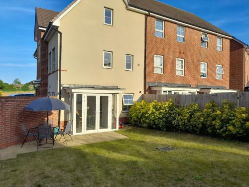 a house with a patio and an umbrella in the yard at Beautiful 4 Bedroom Treasure home in Hemel Hempstead
