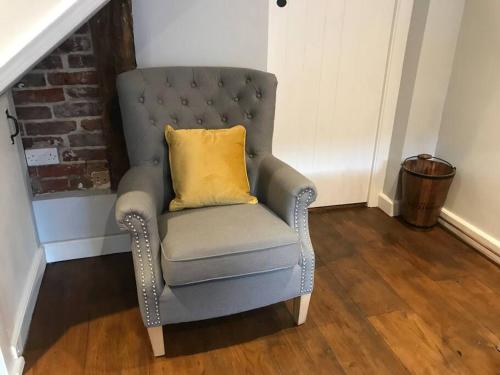 a gray chair with a yellow pillow in a room at Boutique style cottage Bridgnorth in Bridgnorth