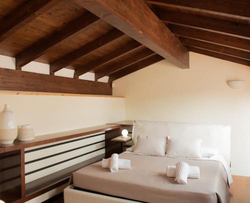 una camera da letto con letto, lenzuola bianche e soffitti in legno di Residenza Sweet Juliet a Verona