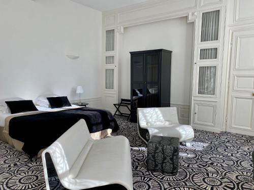 a white bedroom with a bed and two white chairs at Hôtel Particulier de Champrond in Chartres