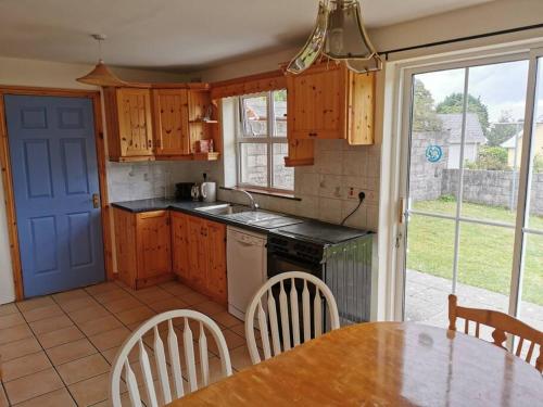 a kitchen with wooden cabinets and a table with chairs at The Cobbler Rosscarbery Holiday Cottage in Rosscarbery