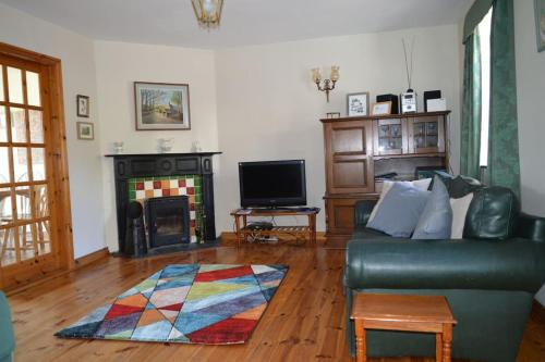 sala de estar con sofá y chimenea en The Cobbler Rosscarbery Holiday Cottage, en Rosscarbery
