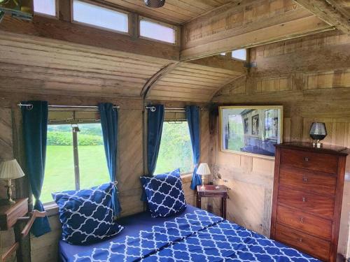 a bedroom with a blue bed in a tiny house at L'Express Voiture-Salon n°14630 in Sierville