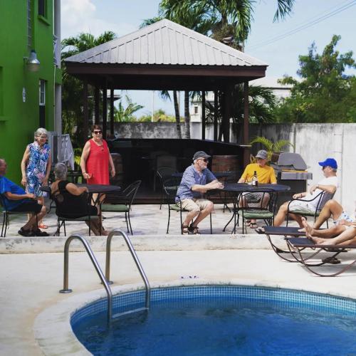 a group of people sitting around a swimming pool at Best E Villas Prospect St James in Saint James