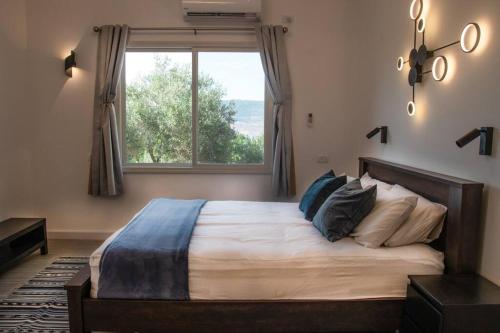 een slaapkamer met een groot bed en een raam bij הבית ליד הבוסתן in Mikhmannim