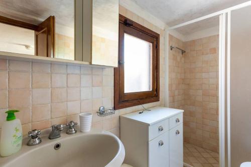 baño con bañera, lavabo y ventana en Casa Velio en Castiglione della Pescaia