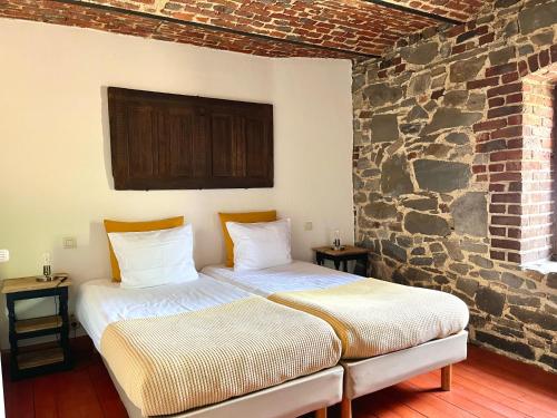 twee bedden in een kamer met een stenen muur bij La Bushaye in Aubel