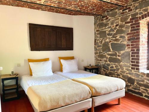 two beds in a room with a stone wall at La Bushaye in Aubel