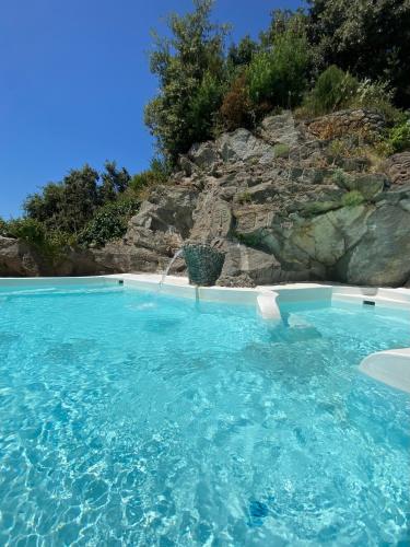a swimming pool with blue water in front of a cliff at Villa Marecoco in Forio d'Ischia