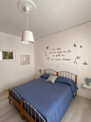 una camera da letto con un letto con lenzuola blu e parole sul muro di Casa Matilde a Capaccio-Paestum