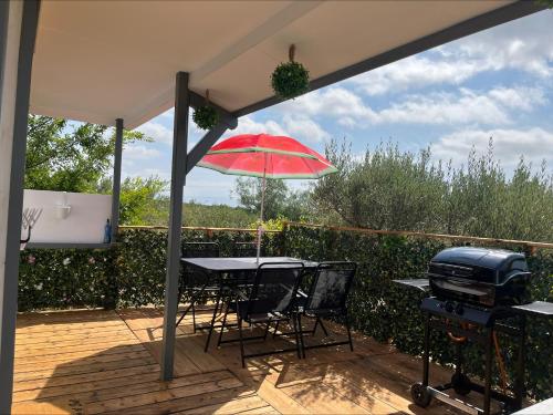 a patio with a table and a red umbrella at Chalet Espagne EL FARO 4/6p in Camarles
