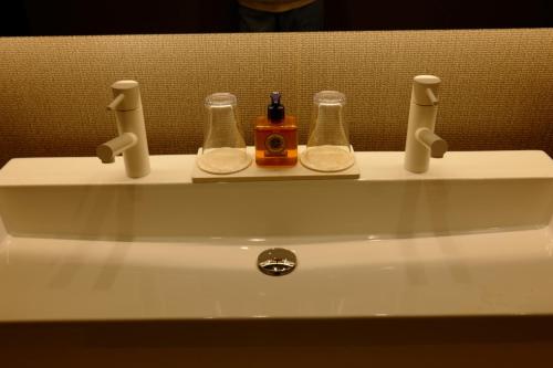 a bathroom sink with two bottles and a soap dispenser on it at 椿邸・TSUBAKI-Tei in Jozankei