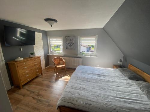 a bedroom with a bed and a dresser and two windows at Ferienhaus Glückszeit bei Goslar in Langelsheim