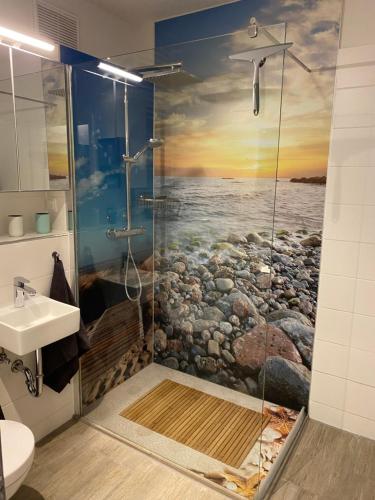 a bathroom with a shower with a painting of the ocean at Ferienwohnung Lieblingsplatz in Sierksdorf