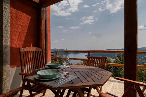 uma mesa de madeira com tigelas e pratos numa varanda em Casa Belvedere Egro - tiny house em Cesara