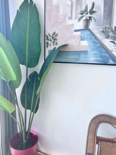 Una planta en una maceta roja junto a un cuadro. en LA PLAGE, en La Grande-Motte