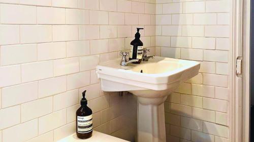 a white bathroom with a sink and two bottles at Lovely 3-Bed Apartment & garden & dog friendly in London