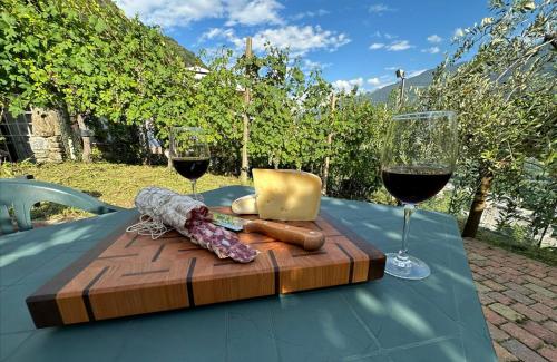 - une planche à découper en bois avec du fromage et des verres à vin sur une table dans l'établissement Casa dell'Olivo, à Castione Andevenno