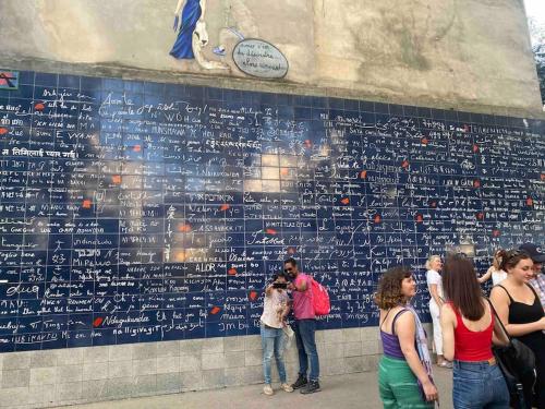 a group of people standing in front of a wall with writing at T2 Sacré Cœur - Butte Montmartre - Abbesses in Paris