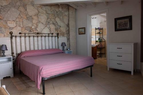 um quarto com uma cama e uma parede de pedra em Elmani em Pozzallo