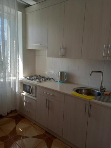 卡緬涅茨波多利斯基的住宿－Apartment on Kniaziv Koriatovychiv，厨房配有白色橱柜、水槽和窗户。