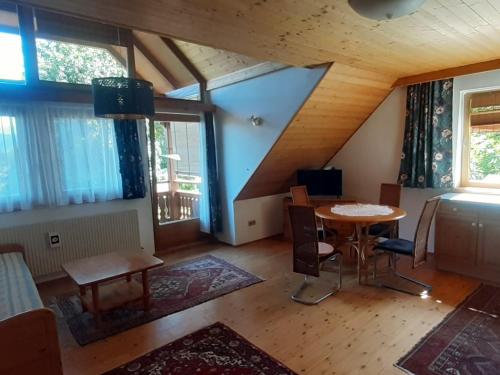 an attic room with a table and chairs and windows at Singer-Hof in Krumpendorf am Wörthersee