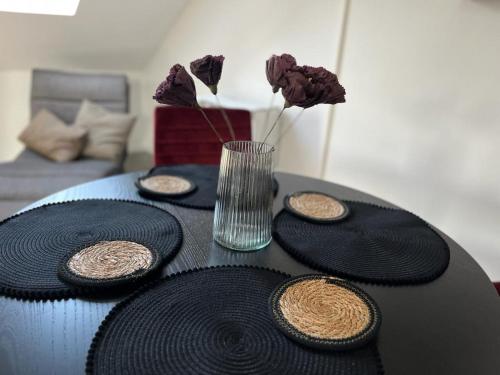 einen Tisch mit schwarzen Platten und eine Vase mit Blumen in der Unterkunft Willkommen Zuhause - Traumhafte, zentrale Ferienwohnung in Kurstadt in Bad Oeynhausen